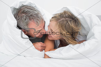 Loving middle aged couple under the duvet