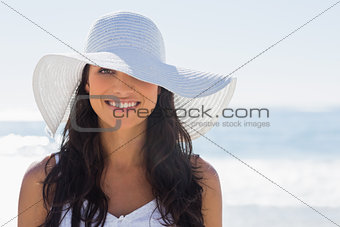 Pretty brunette in white sunhat smiling at camera