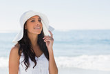 Beautiful brunette in white sunhat looking away and touching hat