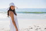 Brunette in white sunhat looking over her shoulder at camera
