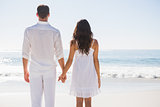 Attractive couple holding hands and watching the ocean