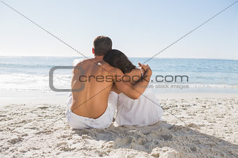 Couple sitting on the sand watching the sea