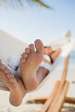 Close up of sandy feet of woman sleeping in a hammock