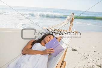 Woman lying on hammock reading book