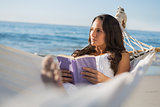 Woman lying on hammock holding book and thinking