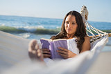 Content woman lying on hammock reading book
