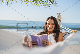 Peaceful woman lying on hammock reading book
