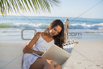 Pretty brunette sitting on hammock with laptop