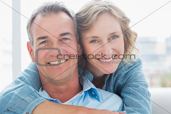 Smiling woman hugging her husband on the couch from behind