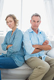 Middle aged couple sitting on the sofa not speaking after a dispute