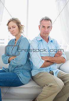 Middle aged couple sitting on the sofa not speaking after a dispute