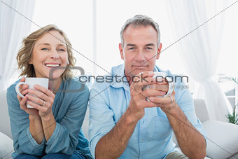 Content middle aged couple sitting on the couch having coffee