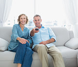 Content middle aged couple sitting on the couch watching tv