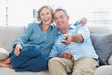 Cheerful couple cuddling and sitting on the couch watching tv