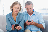 Smiling couple using their smartphones