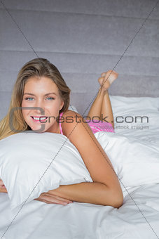 Cheerful blonde lying on her bed smiling