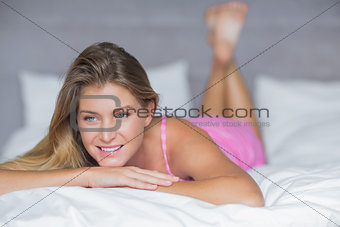 Thinking blonde lying on her bed smiling