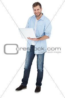 Smiling man using his laptop looking at camera