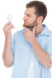 Sceptical model holding a bulb and looking at it