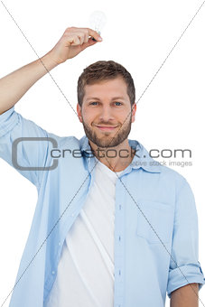 Sceptical model holding a bulb above his head and looking at camera