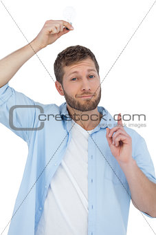 Cheerful model holding light bulb above his head