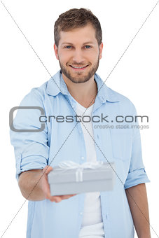 Happy man offering a gift looking at camera