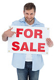 Smiling model holding a for sale sign