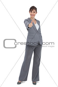 Young businesswoman looking at camera giving thumb up