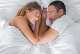 Cute couple lying and looking at each other in bed