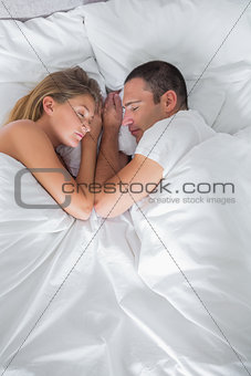 Cute couple lying asleep in bed overhead shot