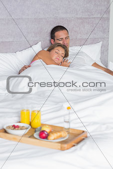 Couple asleep with breakfast tray on bed