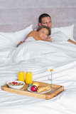 Attractive couple asleep with breakfast tray on bed