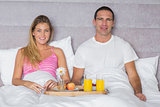 Attractive couple having breakfast in bed
