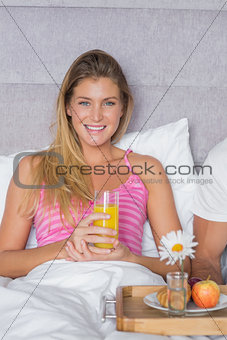 Happy young woman having breakfast in bed with partner