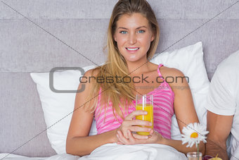 Smiling young woman having breakfast in bed with partner