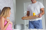 Pretty woman surprised by partner bringing breakfast in bed