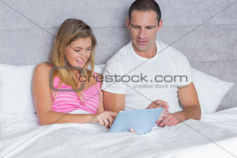 Attractive young couple using their tablet pc together in bed