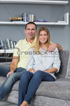 Cheerful young couple sitting on their couch