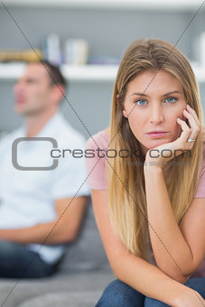Couple not talking after a dispute on the couch with woman looking at camera