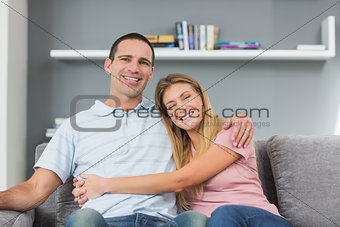 Couple sitting on the couch smiling at camera
