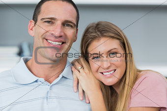 Happy couple sitting on the couch smiling at camera