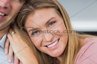 Happy couple sitting on the couch smiling at camera focus on woman