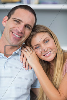 Cute couple sitting on the couch smiling at camera