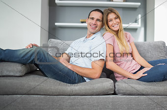 Relaxed couple sitting back to back on the couch together