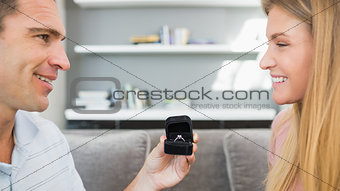 Happy man proposing to his girlfriend on the sofa