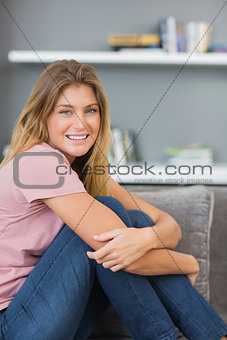 Smiling blonde sitting on her sofa