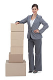 Serious businesswoman with cardboard boxes on her side