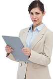 Serious businesswoman with clipboard and looking at camera