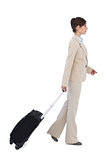 Serious businesswoman pulling suitcase