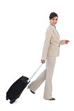 Cheerful businesswoman pulling suitcase